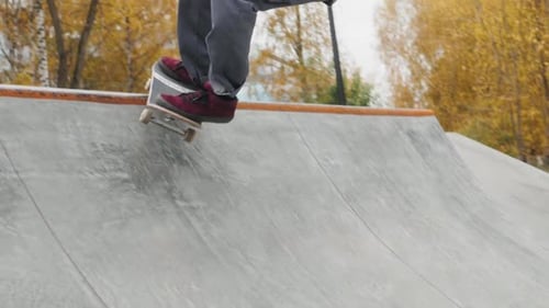 Skater Practicing in the Autumn Concrete Skate Park Making Tricks and Rides in Ramp