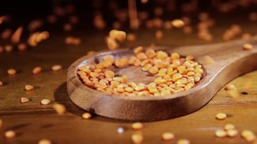 Red Lentils Pouring into Wooden Spoon