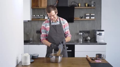 Man Adding Ingredients To Pot In Modern Kitchen