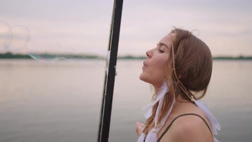 Woman Blowing Bubbles by Lake