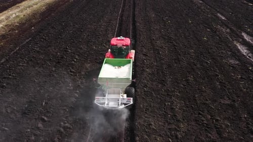 Tractor Spreads Dry Mineral Fertilizers on a Field