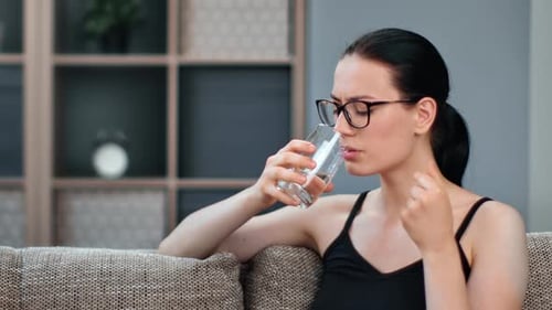 Woman Takes Pill With Water Indoors