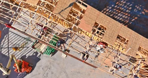 An Installation Crane Holds Roof Truss Beams on a Wooden Roof