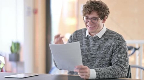 Man Reads Document, Smiles with Satisfaction