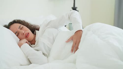Woman Lying in Bed with Stomach Pain
