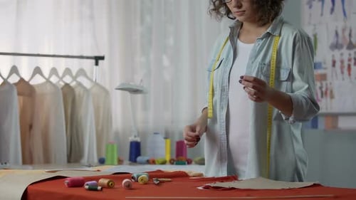 Näherin steckt Faden in die Nadel und fängt an, Teile der Kleidung zusammenzunähen