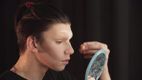 Young Adult Applying Makeup with Handheld Mirror
