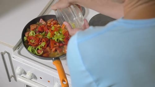 Man Adding Peppers to Vegetable Dish