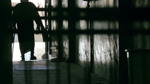 Dark Figure Walks with Object Near Concrete Walls