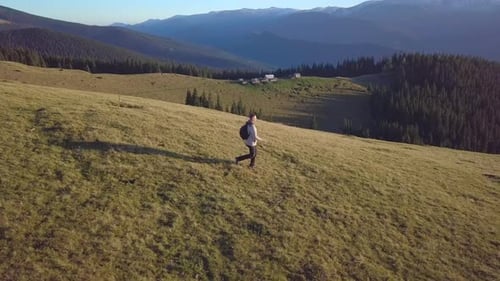 Hiker Walking Across Grassy Mountain Slope