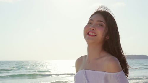 Young Asian woman walking on beach near sea when sunset in evening. Lifestyle women travel.