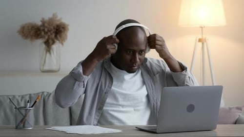 Man Wearing Headphones Typing at Laptop Indoors