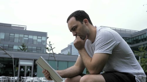 Serious Casual Man Using Digital Tablet Sitting Outdoors.
