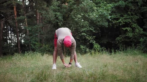 Young Asian Man Warming Up at Forest Road Before Jogging