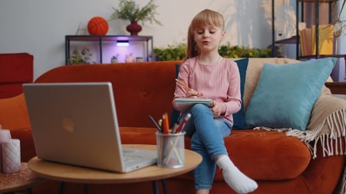 Adorable Girl Drawing in a Notebook at Home