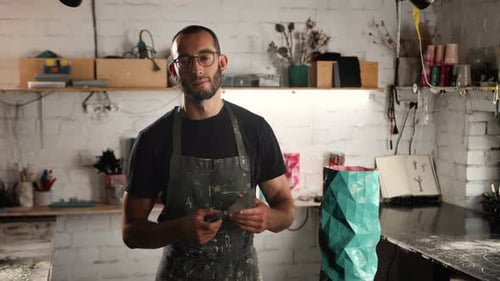 Retrato de um homem, de perto: um homem de óculos de aparência árabe olha para a câmera e sorri.