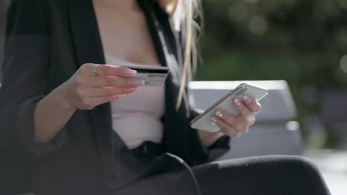 Woman on Bench with Cell Phone and Credit Card