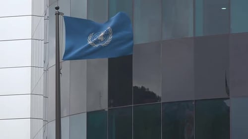 United Nations Flag Waving Before Modern Glass Building