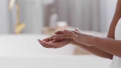 Crème à frotter ou mousse Black Lady méconnaissable dans la paume de la main debout à l'intérieur de la salle de bain
