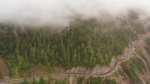 Aerial Scenic View of Road By the Mountains and Fog Covering the Peak