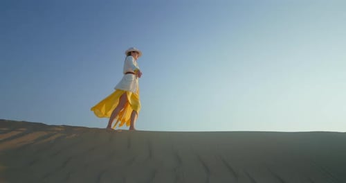 Cheerful Woman with Raised Hands Walking on Sand Dune in Desert
