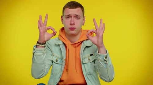 Young Man Gesturing OK Against Yellow Background