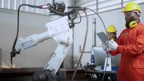 Technischer Ingenieur verwaltet die Tastatureingabe, programmiert die Bewegung des modernen Schweißroboterarms