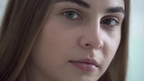 Close-up Portrait of Young Pretty Woman with Different Colored Eyes Looking at Camera in the Morning