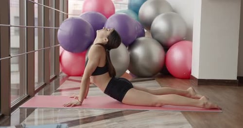 Athletic Woman Stretching on a Mat in a Fitness Studio