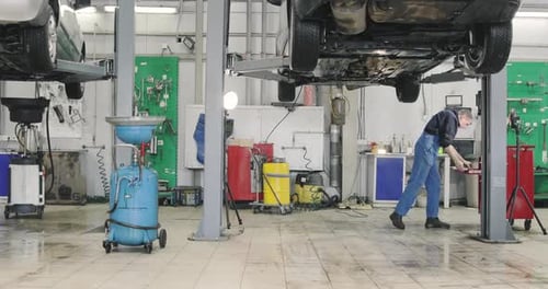 Riesige Auto-Servicezone voller Licht - Automechaniker arbeitet. Weite Aufnahme