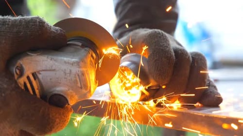 Detail View on Metal Processing with Circular Saw. Hands of Mechanic Holding Instrument and Grinding