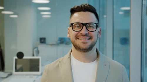 Portrait of Successful Young Businessman in Glasses Smiling Looking at Camera in Office
