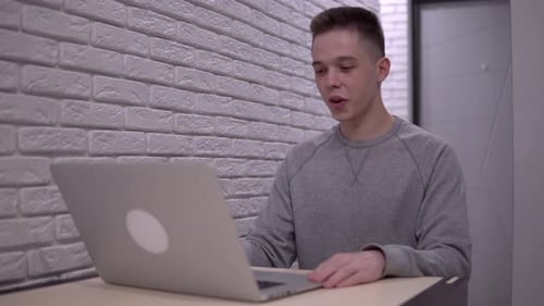 Young Adult Video Conferencing on Laptop Computer Indoors