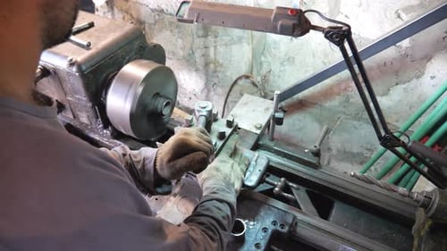Unrecognizable Man Working with Old Workbench in His Garage or Workshop. Mechanic Using Lathe for