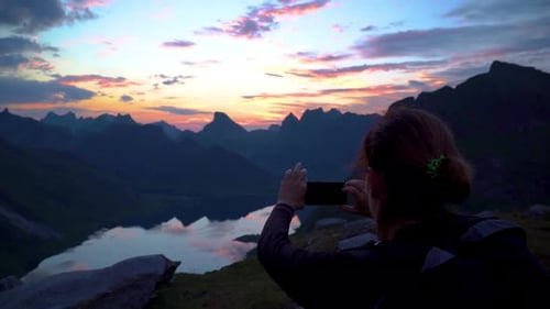 Woman Photographs Mountain Lake at Scenic Sunrise