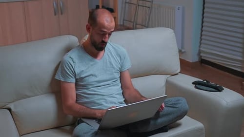 Man Works on Laptop Sitting on Couch