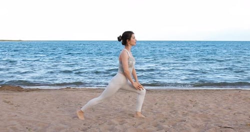 Frau praktiziert Yoga draußen in Kriegerpose am Strand
