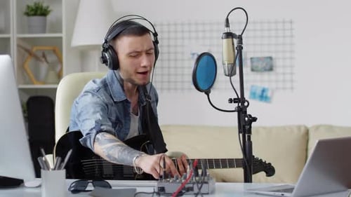Male Singer Playing Guitar and Recording Song in Home Studio