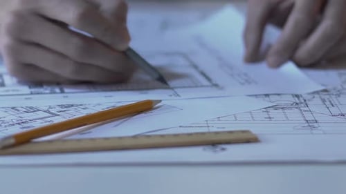 Architect checking building guidelines drawing, design bureau, hands closeup
