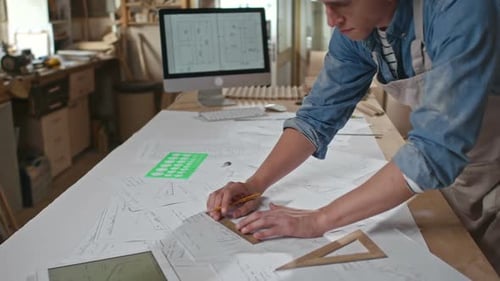 Man Drawing Architectural Plans in Workshop
