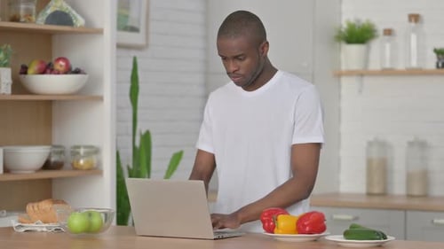Young Adult Typing on Laptop in Kitchen