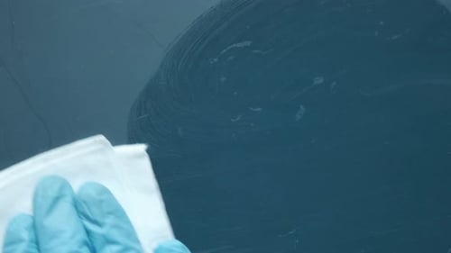 Gloved Hand Cleaning a Dark Blue Surface