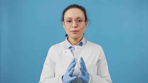 Studio Portrait of Woman Doctor in Eyeglasses Talking to Camera Recording Video Blog