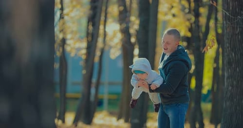 Young Father Spin His Little Son Outdoors