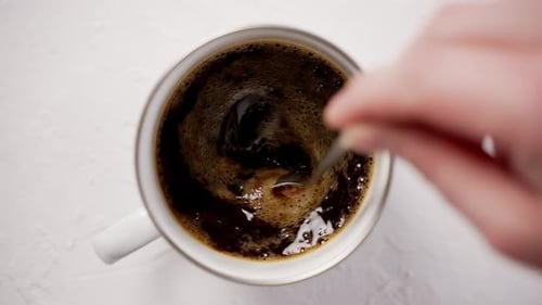 Hand Stirring a Fresh Cup of Black Coffee