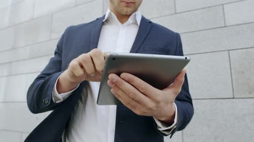Businessman Working on Pad at City street.Business Man Scrolling Tablet Outdoors