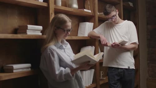 Young Smart Couple in Eyeglasses Reading Books at the Library