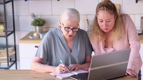 Senior Woman Learning Computer with Young Adult Woman