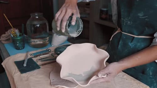 Potter Pouring Liquid into Clay Bowl in Studio