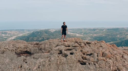 Young climber celebrates the top of the mountain with open arms